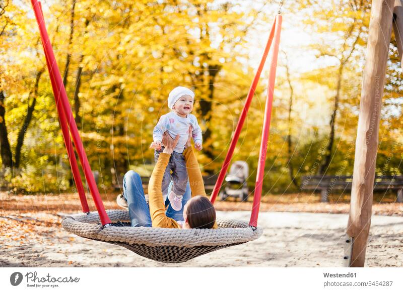 Happy baby girl relaxing with her mother on a swing in autumn fall relaxation relaxed mommy mothers ma mummy mama infants nurselings babies swing set