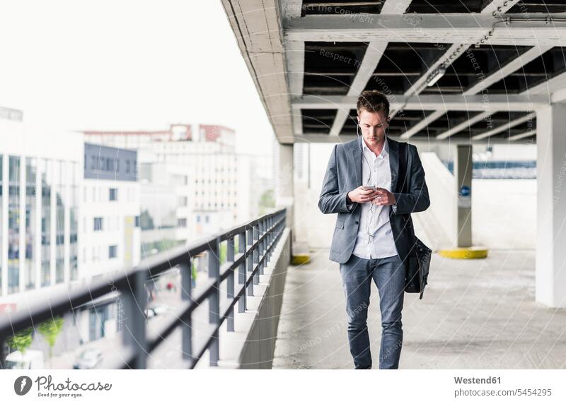 Young businessman using smartphone, walking on parking level on the move on the way on the go on the road urban urbanity Smartphone iPhone Smartphones call