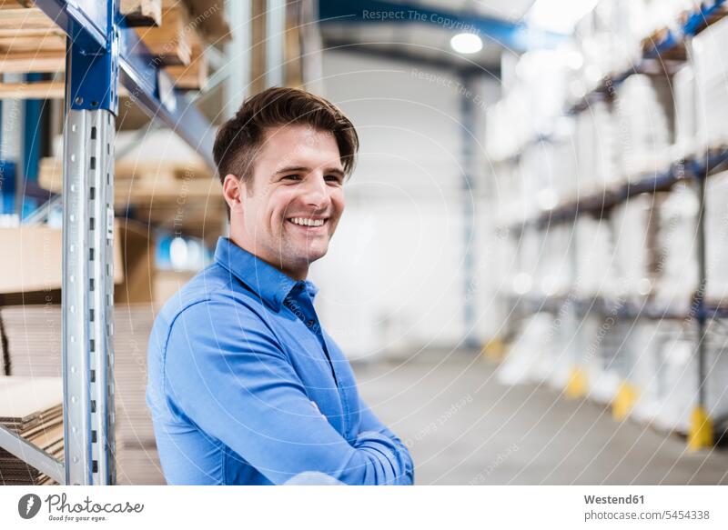 Businessman standing in warehouse, portrait factory storehouse storage working At Work product products happiness happy confidence confident smiling smile