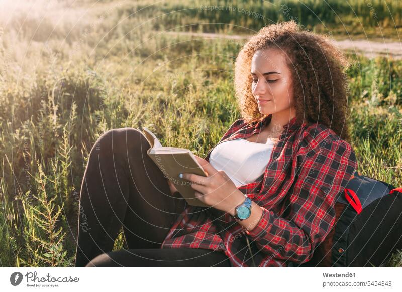 Teenage girl reading book on a meadow books Teenage Girls female teenagers portrait portraits Teenager Teens people persons human being humans human beings
