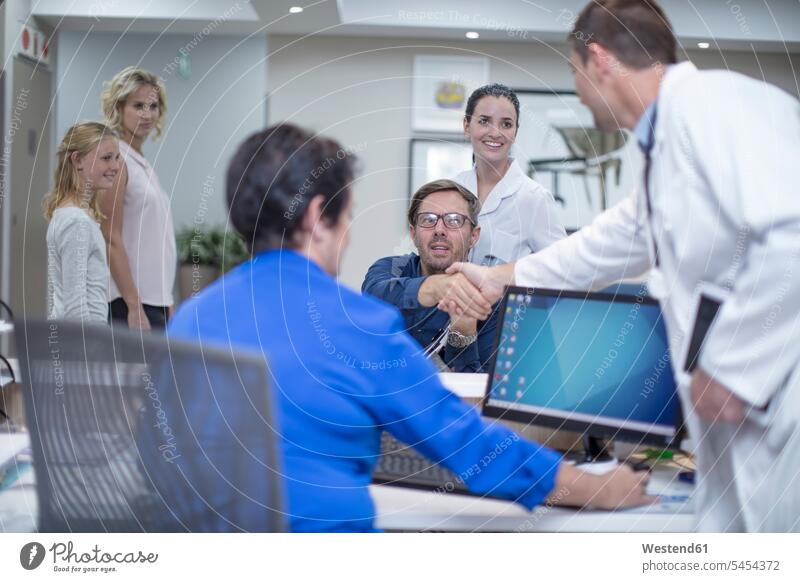 Patient in wheelchair greeting doctor at the reception patient patients clinic hospitals Medical Clinic physicians doctors illness disease Sickness illnesses
