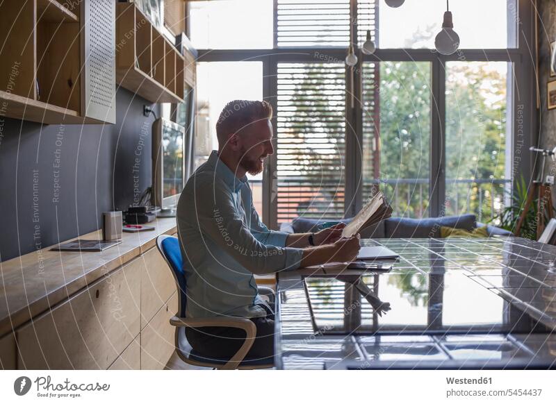Man reading newspaper at home newspapers Businessman Business man Businessmen Business men freelancer freelancing business people businesspeople business world