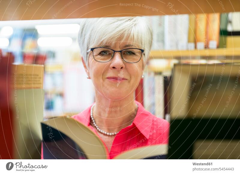 Portrait of smiling senior woman with book in a city library books portrait portraits building buildings built structure built structures senior women