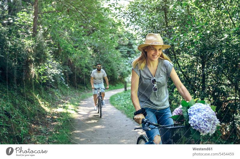 Couple riding bicycle in a forest bikes bicycles woods forests couple twosomes partnership couples riding bike bike riding cycling bicycling pedaling people