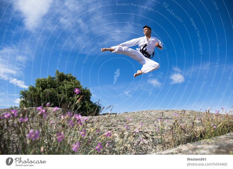 Man doing a jump kick during a martial arts training exercising exercise practising jumping Leaping kicking combative sport man men males fighting jumps sports