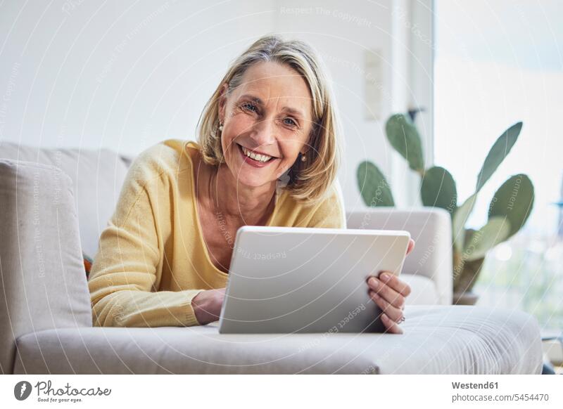 Smiling mature woman at home using tablet on the sofa digitizer Tablet Computer Tablet PC Tablet Computers iPad Digital Tablet digital tablets lying laying down