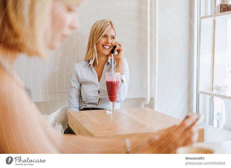 Young women on cell phone in a cafe smoothie Smoothies mobile phone mobiles mobile phones Cellphone cell phones smiling smile woman females Drink beverages