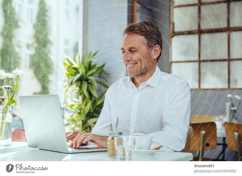 Smiling businessman working in cafe with laptop Laptop Computers laptops notebook At Work smiling smile Businessman Business man Businessmen Business men