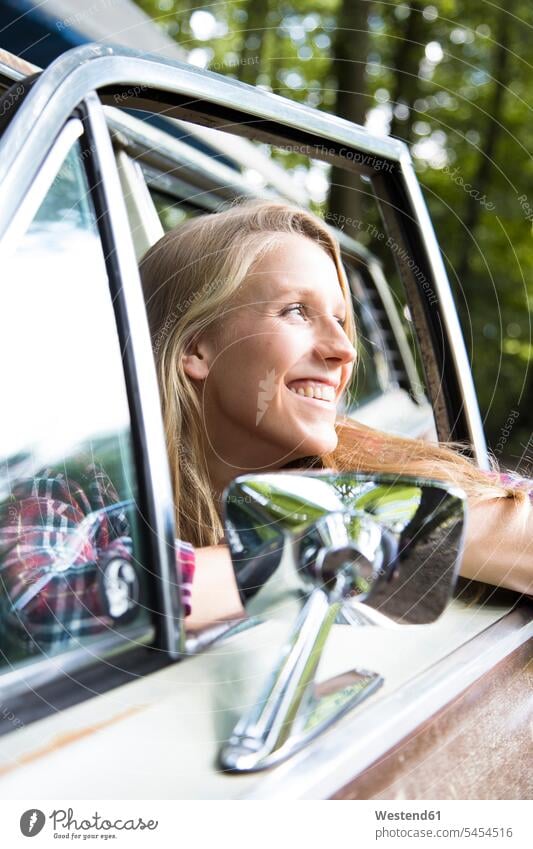 Happy young woman in car in forest woods forests happiness happy females women automobile Auto cars motorcars Automobiles Adults grown-ups grownups adult people