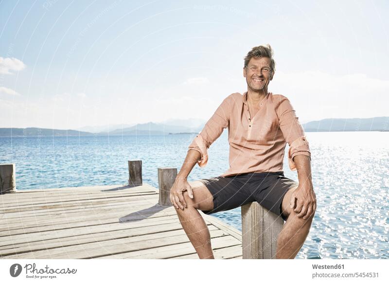 Portrait of smiling man sitting on jetty portrait portraits men males Adults grown-ups grownups adult people persons human being humans human beings Sea ocean