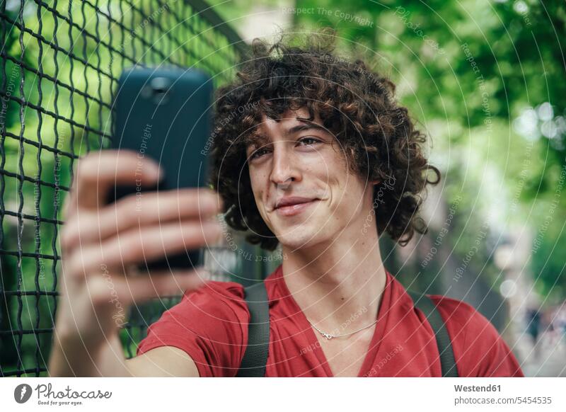 Young man taking a selfie with smartphone Selfie Selfies mobile phone mobiles mobile phones Cellphone cell phone cell phones men males telephones communication