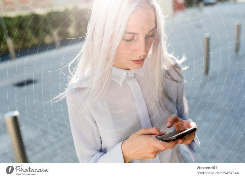Young businesswoman checking cell phone in the city serious earnest Seriousness austere businesswomen business woman business women females mobile phone mobiles