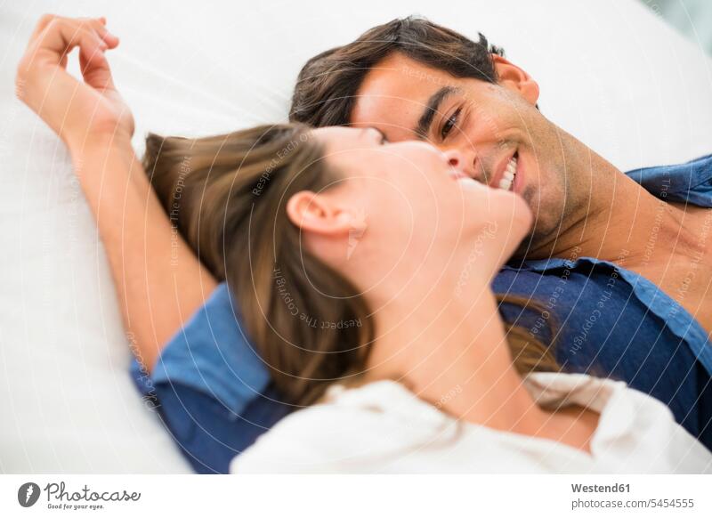Smiling young couple in love lying down relaxed relaxation laying down lie smiling smile twosomes partnership couples relaxing people persons human being humans