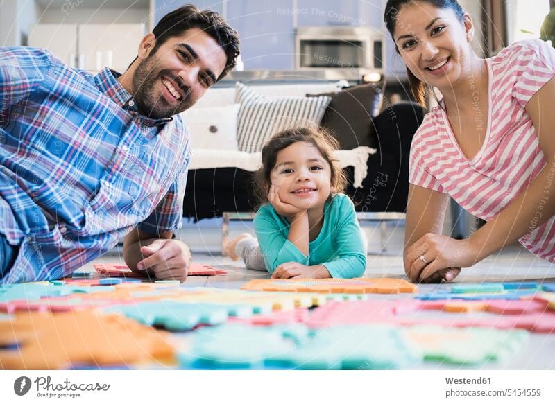 Happy family sitting on floor, playing with daughter home at home families floors puzzle jigsaw puzzle Seated learning people persons human being humans