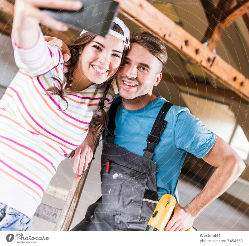 Young couple renovating their new home, taking smart phone selfies DIY Doityourself Do it yourself Do-it-yourself twosomes partnership couples cheerful gaiety