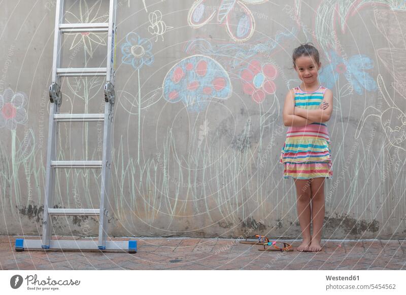 Girl standing next to colourful pictures on a concrete wall concrete walls girl females girls multi-coloured multicoloured multi colored Multi Coloured colorful