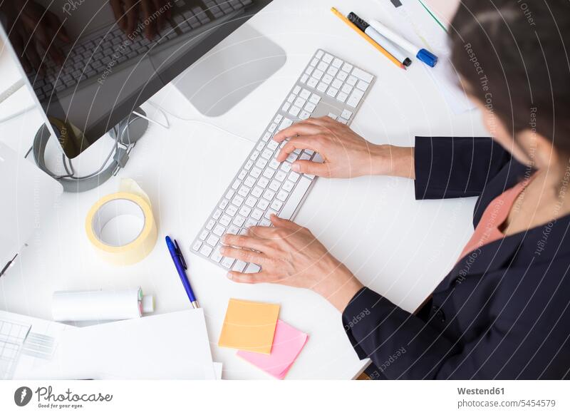 Woman using computer keyboard at desk in office offices office room office rooms desks keyboards workplace work place place of work Table Tables business