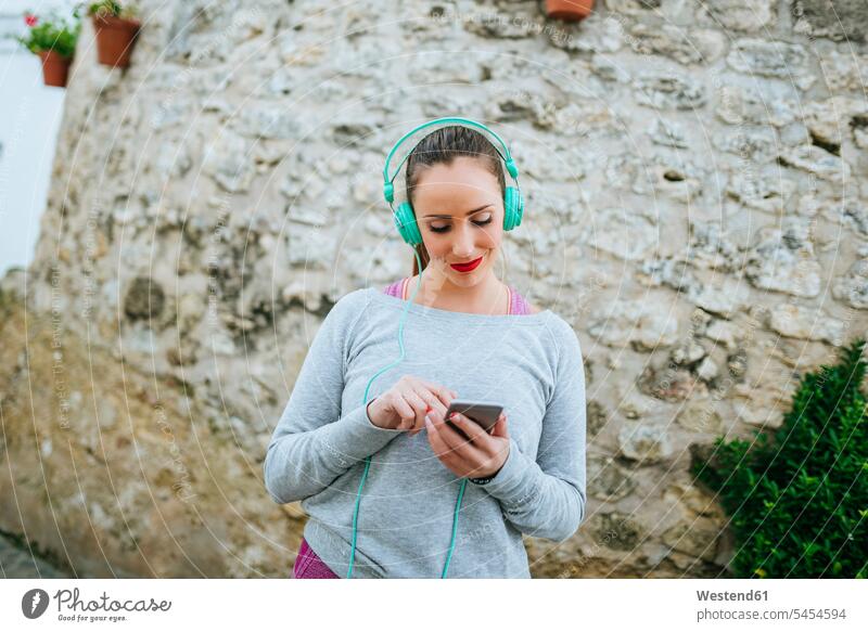 Young woman with headphones sending message with mobile phone females women Smartphone iPhone Smartphones reading text messaging SMS Text Message