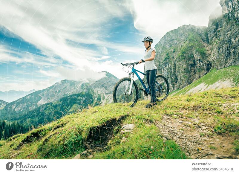 Germany, Bavaria, Pfronten, smiling teenage girl with mountain bike on alpine meadow near Aggenstein View Vista Look-Out outlook standing smile Teenage Girls