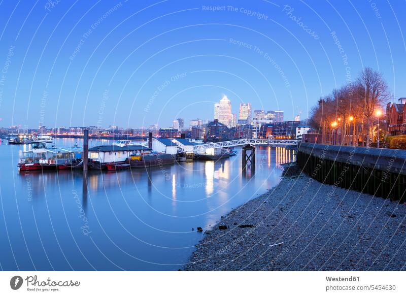 UK, London, floating workshops on River Thames and Canary Wharf in background at blue hour evening in the evening Skyline Skylines Urban Skyline urban scene