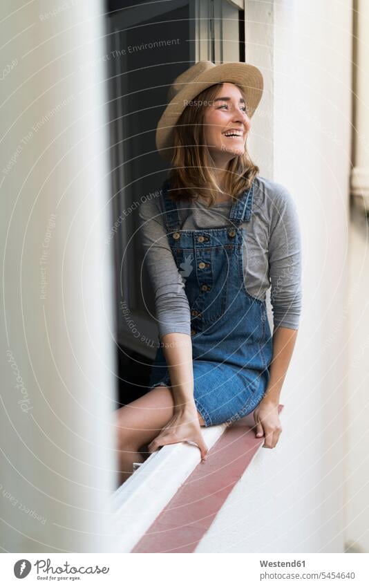 Happy young woman sitting in window frame Seated laughing Laughter females women positive Emotion Feeling Feelings Sentiments Emotions emotional Adults