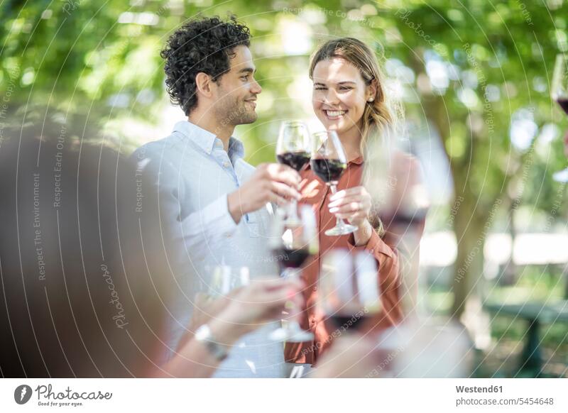 Couple raising a toast together with wine in garden Red Wine Red Wines friends celebrating celebrate partying group of people Group groups of people family