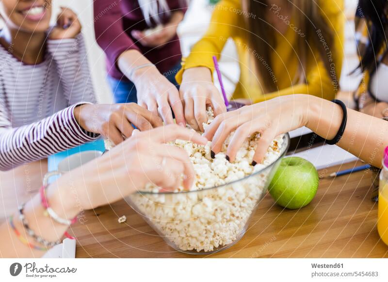 Friends taking popcorn from bowl at table at home Bowl Bowls female friends Table Tables student female students woman females women take Popcorn Popcorns mate