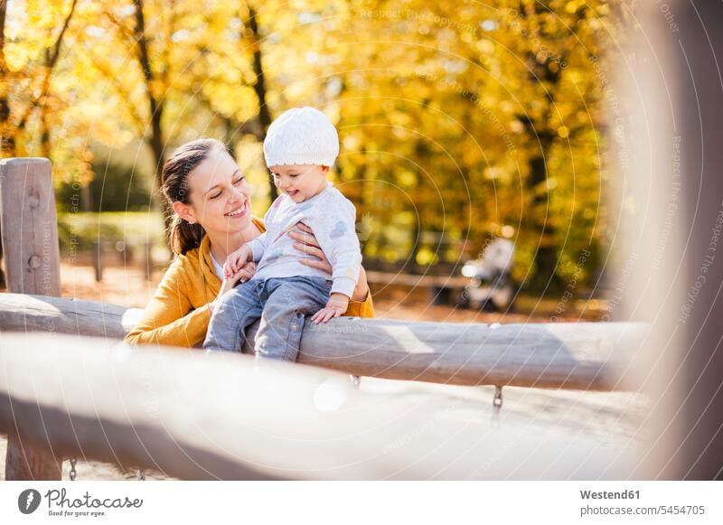 Happy baby girl and her mother having fun on a playground in autumn fall play yard play ground playgrounds baby girls female mommy mothers mummy mama happiness