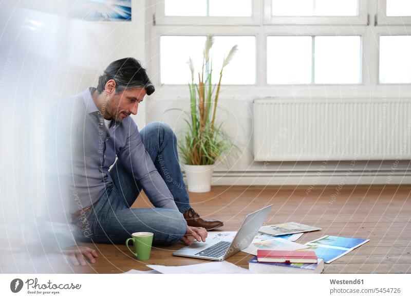 Man using laptop on the floor in office Laptop Computers laptops notebook working At Work Businessman Business man Businessmen Business men males offices