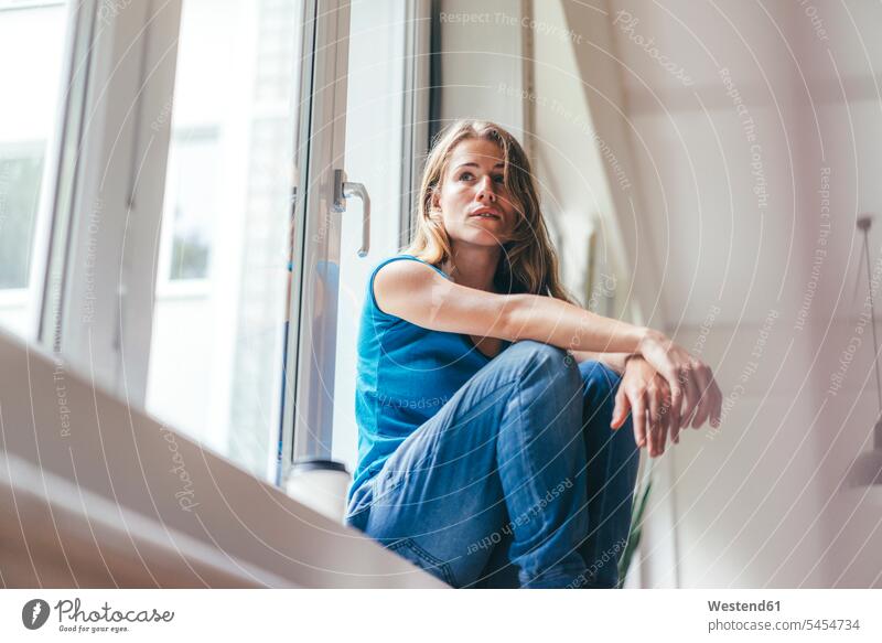 Young woman sitting at the window Seated females women windows Adults grown-ups grownups adult people persons human being humans human beings home at home