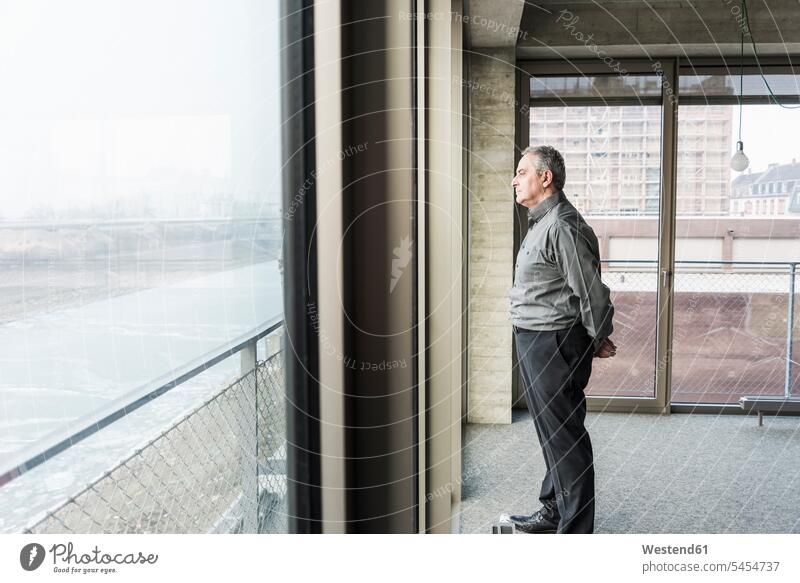 Senior businessman looking out of window windows serious earnest Seriousness austere Businessman Business man Businessmen Business men view seeing viewing
