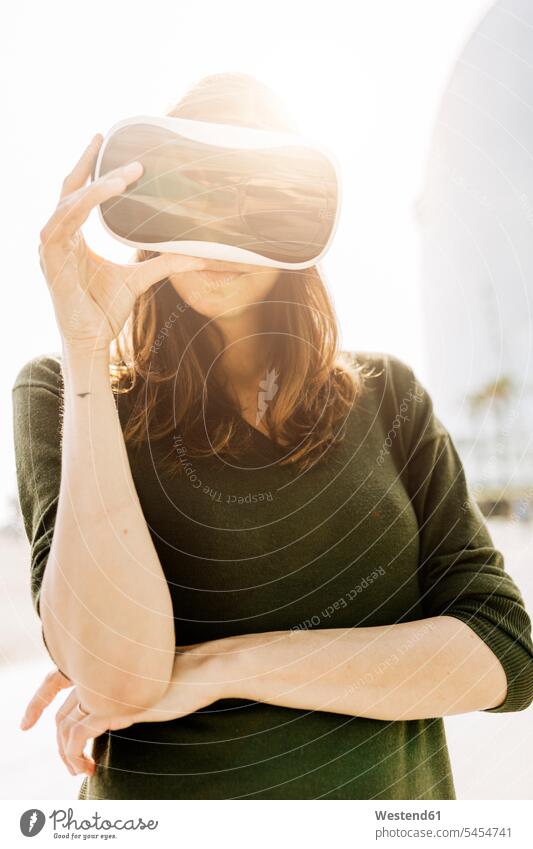 Young woman wearing VR glasses outdoors virtual reality females women Adults grown-ups grownups adult people persons human being humans human beings Spain 3D