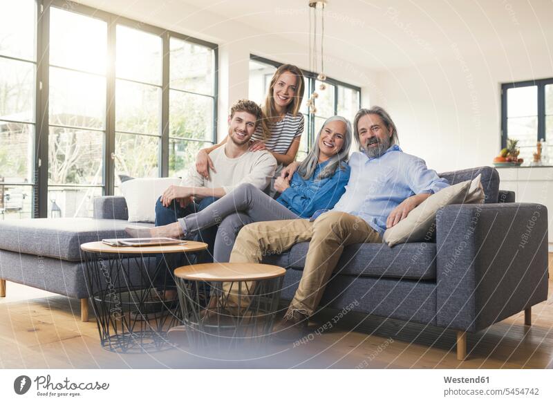 Senior couple with family sitting on couch happiness happy families cozy sociable comfortable cosy settee sofa sofas couches settees together Seated home