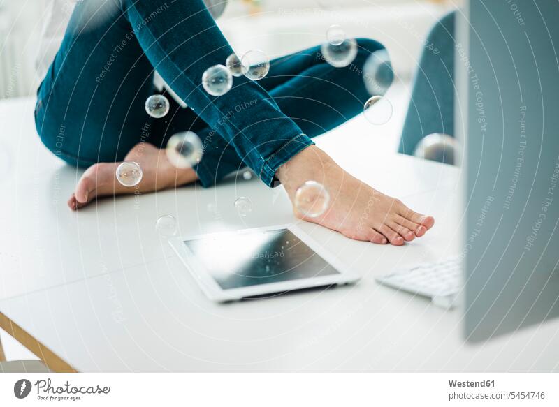 Close-up of businesswoman sitting on desk in office with tablet and soap bubbles Office Offices businesswomen business woman business women digitizer