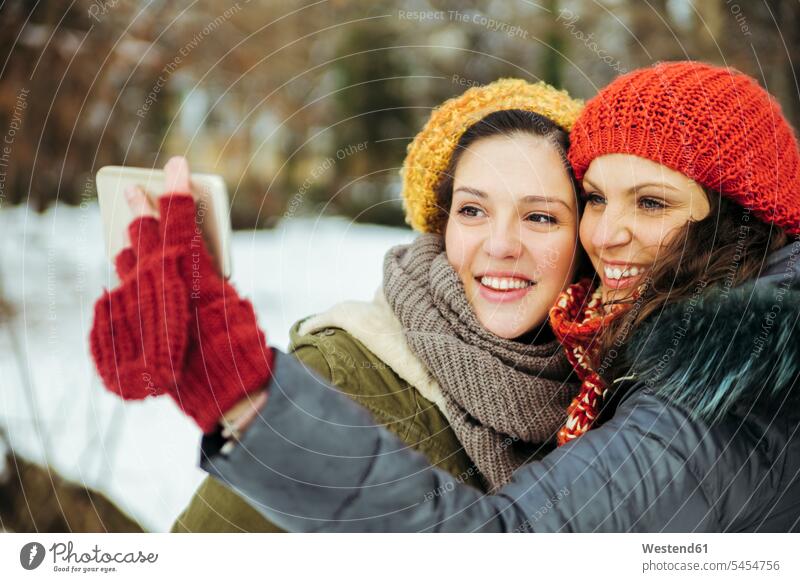 Two friends taking selfies in the snow Selfie Selfies female friends mate friendship winter hibernal Smartphone iPhone Smartphones laughing Laughter