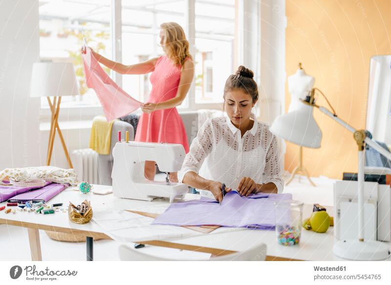Two young women in fashion studio sewing studios fashionable woman females Adults grown-ups grownups adult people persons human being humans human beings