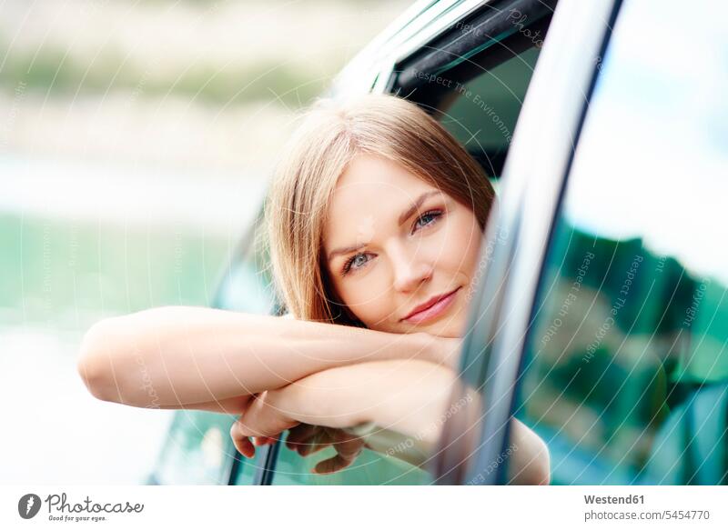 Portrait of young woman leaning out of car window automobile Auto cars motorcars Automobiles windows females women motor vehicle road vehicle road vehicles