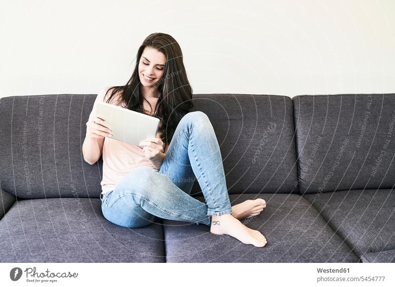 Smiling young woman sitting on couch using tablet relaxed relaxation digitizer Tablet Computer Tablet PC Tablet Computers iPad Digital Tablet digital tablets