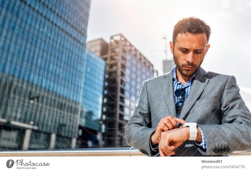 Businessman checking the time in the city Business man Businessmen Business men wrist watch Wristwatch Wristwatches wrist watches business people businesspeople