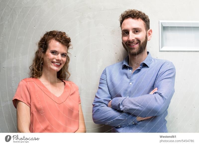 Portrait of smiling man and woman at concrete wall portrait portraits smile concrete walls business business world business life caucasian caucasian ethnicity