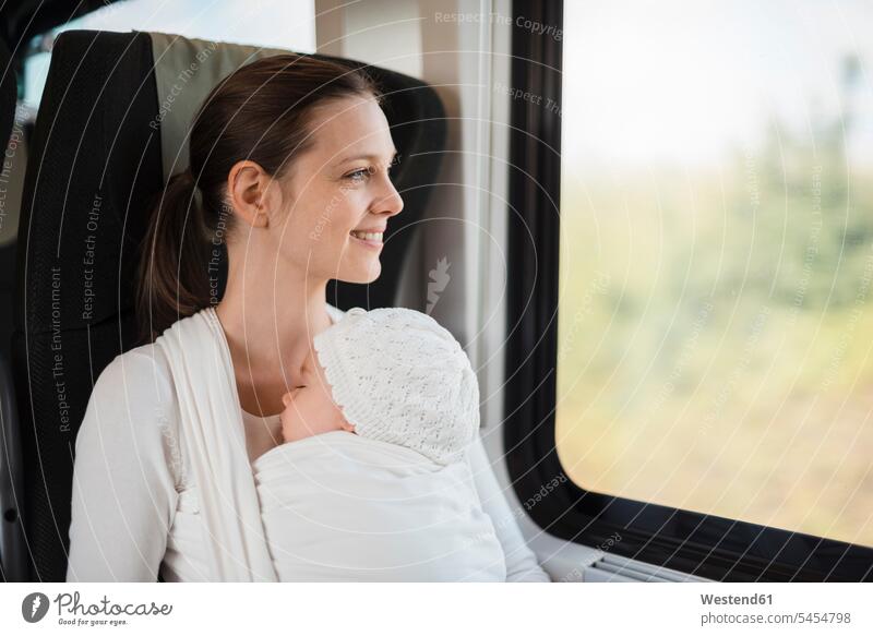 Mother with baby girl traveling by train looking out of window infants nurselings babies mother mommy mothers ma mummy mama travelling windows smiling smile