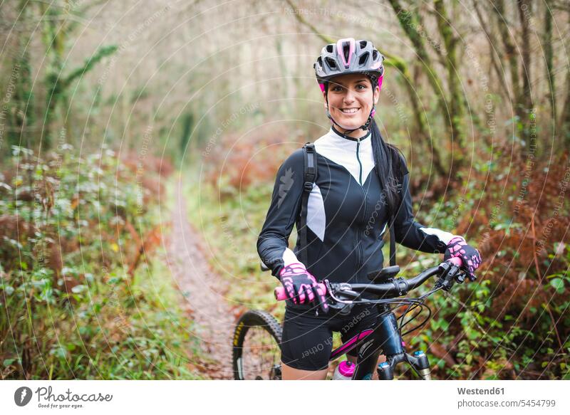 Portrait of smiling woman with mountain bike in forest smile mountain biking MTB mountainbiking females women bicycle bikes bicycles cycling sport sports Adults