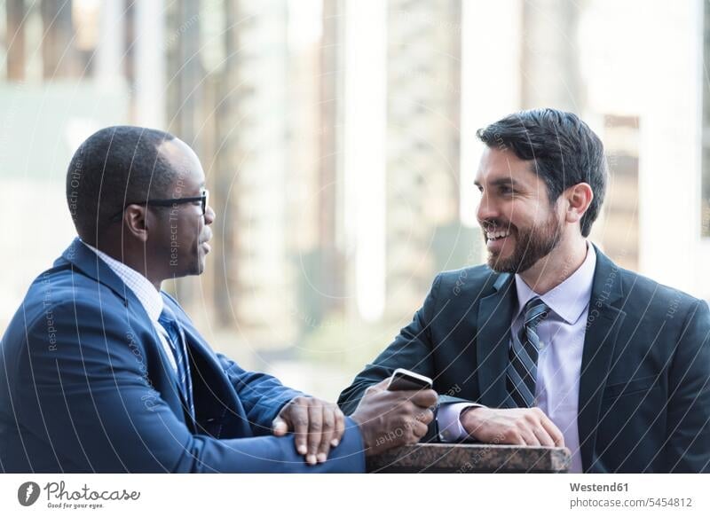 Two businessmen talking outdoors Businessman Business man Businessmen Business men colleagues smiling smile speaking business people businesspeople