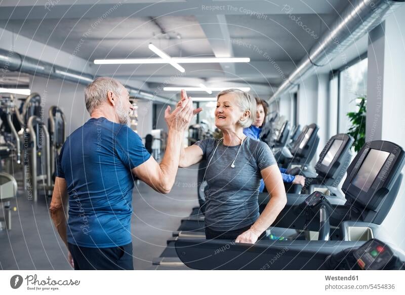 Happy senior man and woman high fiving after working out in gym senior adults seniors old exercising exercise training practising High Five Hi-Five high-fiving