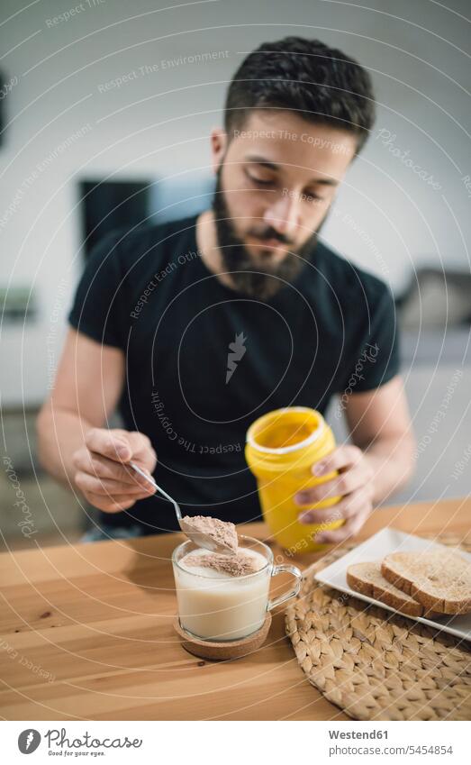 Young man preparing his breakfast at home, mixing cocoa and milk men males Adults grown-ups grownups adult people persons human being humans human beings