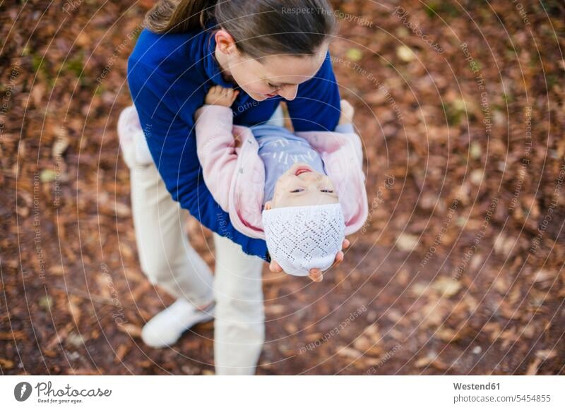 Mother hugging daughter in autumnal park laughing Laughter mother mommy mothers ma mummy mama holding daughters Stroll walk baby girls female playing positive