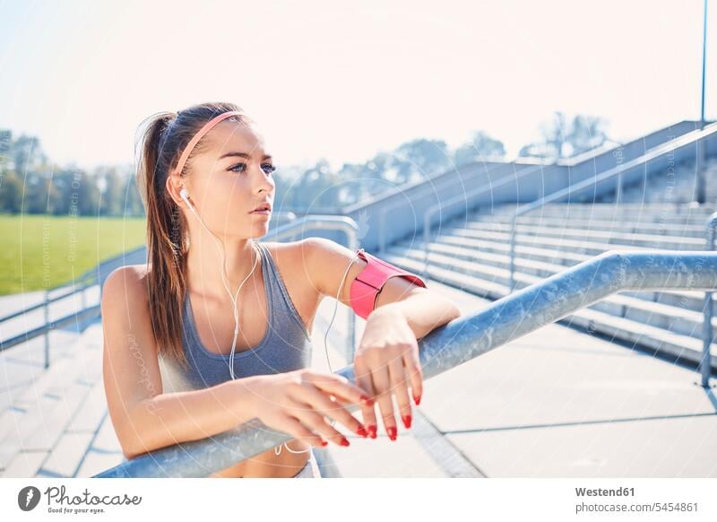 Young woman resting after outdoor workout in the city females women earphones ear phone ear phones urban urbanity working out work out Adults grown-ups grownups