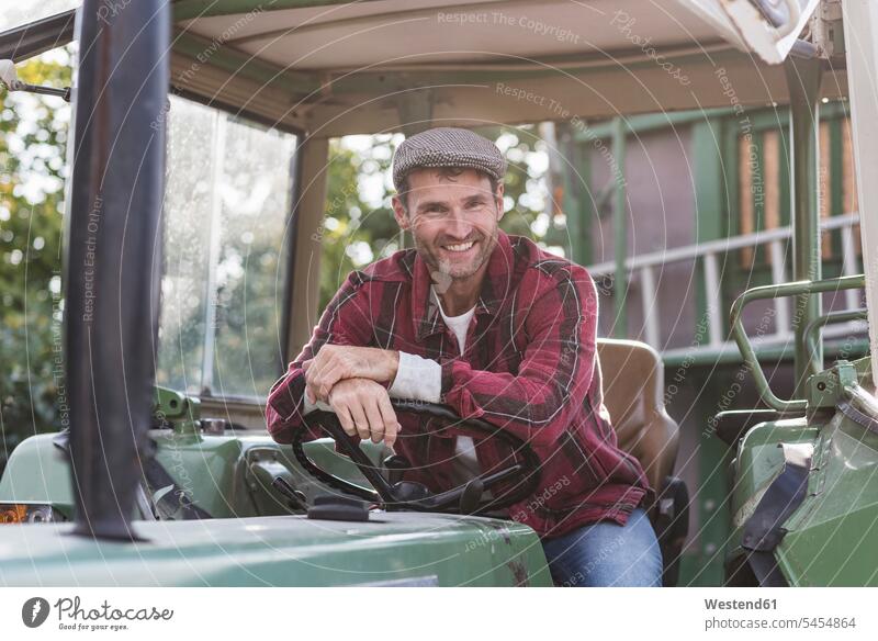Portrait of confident farmer on tractor smiling smile portrait portraits man men males agriculturists farmers Adults grown-ups grownups adult people persons