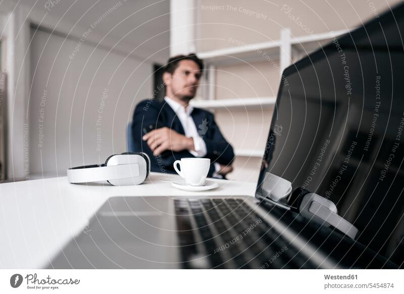 Laptop, headphones, coffee cup and businessman in background Coffee headset Businessman Business man Businessmen Business men males laptop Laptop Computers