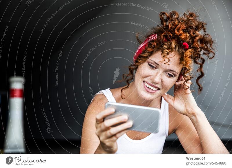 Smiling redheaded woman holding cell phone smiling smile mobile phone mobiles mobile phones Cellphone cell phones females women telephones communication